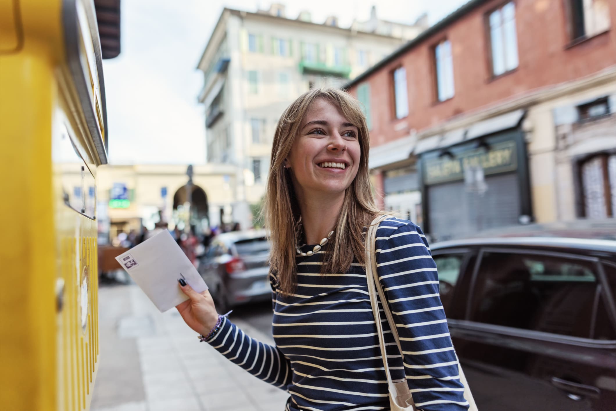 Woman mailing letter in urban street.