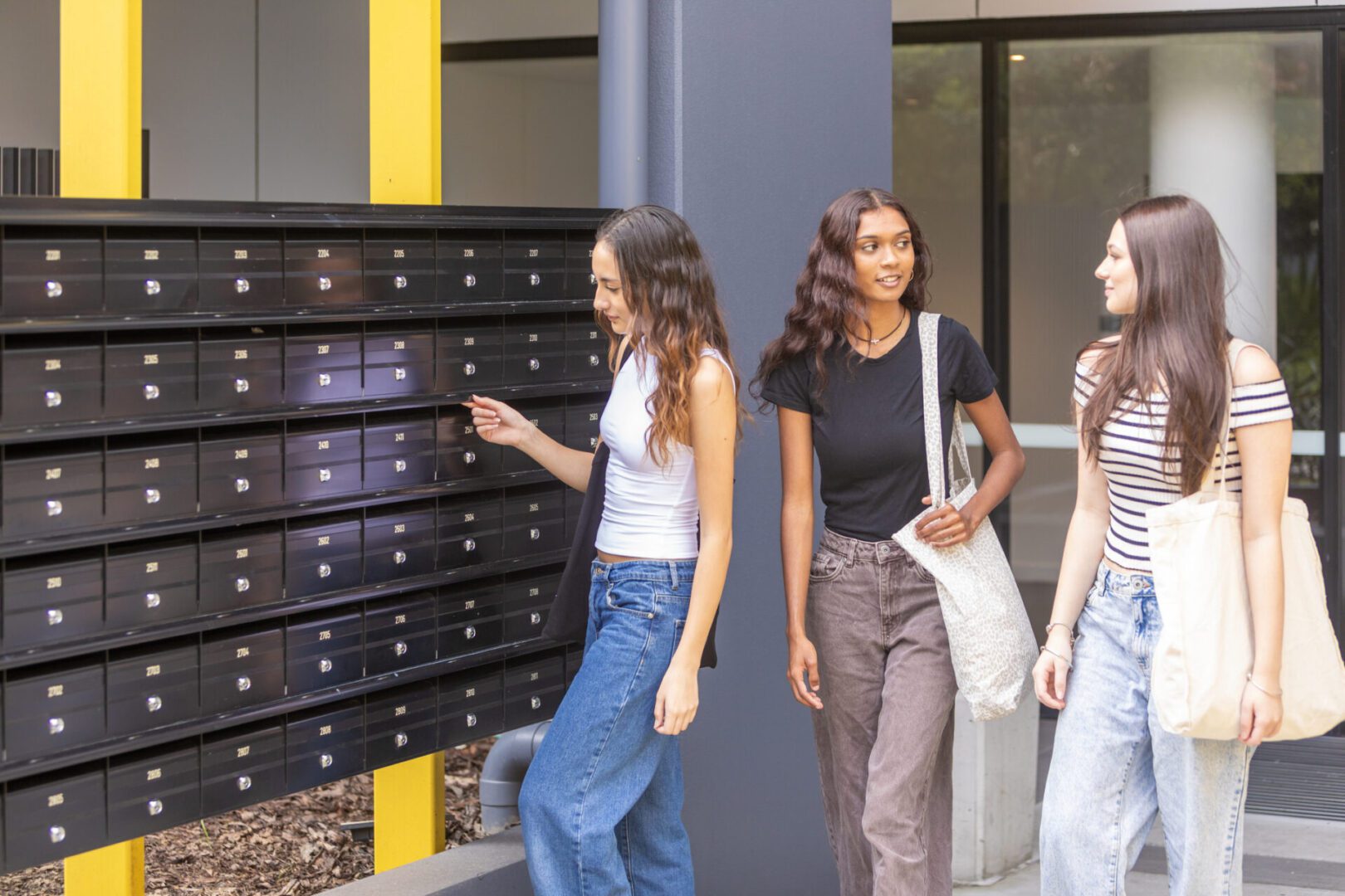 Three women checking outdoor mailboxes together.