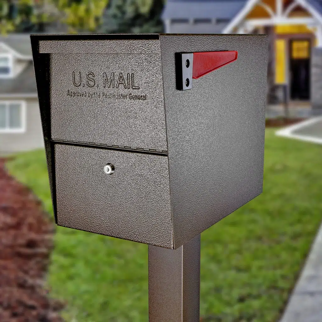 A gray U.S. Mail mailbox on a post in a residential area.